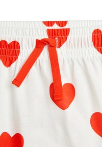 Witte katoenen shorts met grote rode hartpatronen. Voorzien van een geplooide tailleband en een rode trekkoord voor aanpassing.