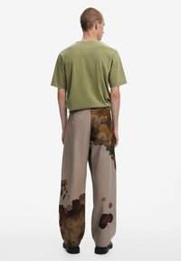Camiseta de algod�ón verde y pantalones beige con acentos de estampado floral, con un corte holgado, tejido texturizado y calzado negro.