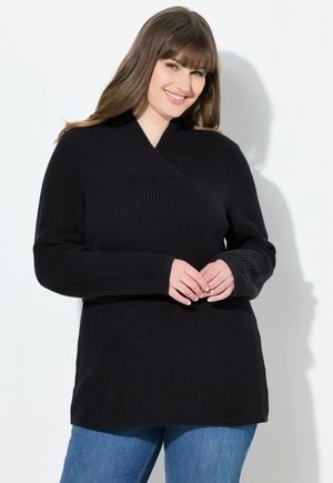 Suéter negro de punto con un diseño de escote en V profundo, mangas largas y textura acanalada. Combinado con jeans azules, que muestran un ajuste relajado.
