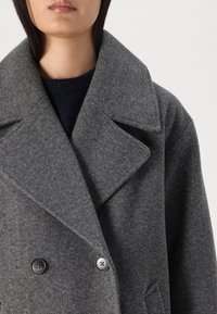 Cappotto peacoat grigio in lana con ampio revers, design doppiopetto, due bottoni neri e dettagli di cucitura ben evidenti. Tessuto testurizzato.