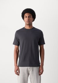 T-shirt à col rond gris foncé en tissu doux, avec des manches courtes et une coupe décontractée. Aucun motif ni accent visible.