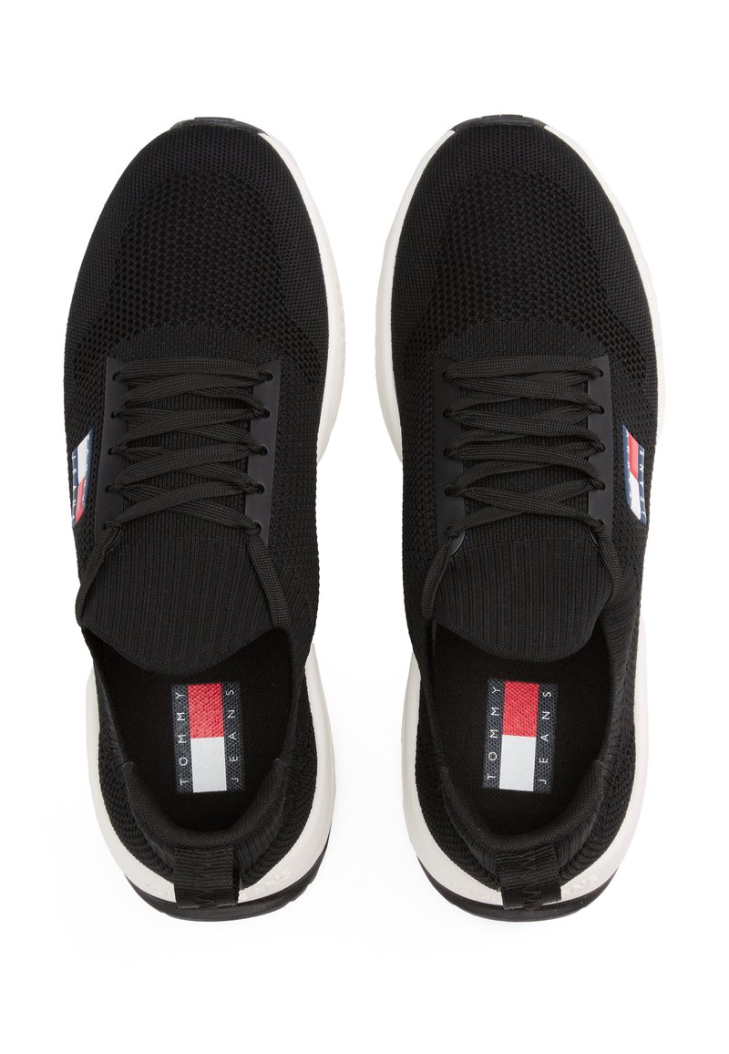 Baskets en mesh noires avec bout arrondi, lacets noirs, tige texturée et semelle blanche. Présente le logo Tommy Jeans sur la languette et sur le côté.