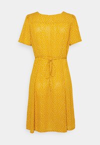 Robe jaune à manches courtes avec des pois blancs, taille à nouer, forme évasée, présentant un col rond et une texture de tissu douce.