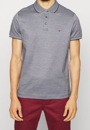 Graues Poloshirt mit gestreiftem Kragen, Knopfleiste mit drei Knöpfen und Logo auf der linken Brust. Kurzärmlig mit passenden gestreiften Akzenten.