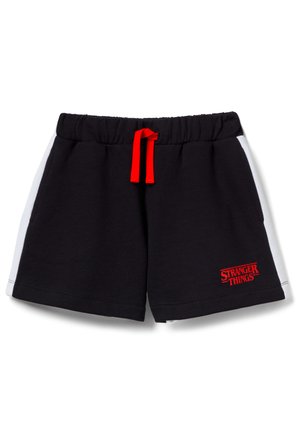 Shorts noirs avec panneaux latéraux blancs, cordon rouge et logo rouge "Stranger Things" sur la partie inférieure de la jambe gauche.