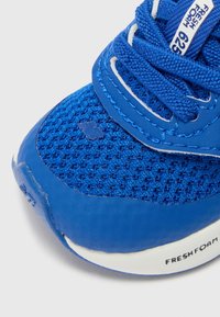 Botte de sport bleue avec une tige en mesh, des revêtements synthétiques, des lacets texturés et une étiquette blanche "FRESH FOAM" sur la semelle intermédiaire.
