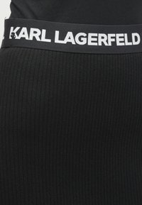 Melna ribota josta ar baltu "KARL LAGERFELD" logotipu, ar maigu tekstūru un elastīgu materiālu. Piemērota dažādiem apģērba izstrādājumiem.