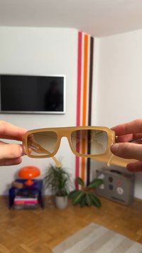 Ochelari de soare translucizi bej cu rame pătrate și lentile maro degradé. Prezintă accente metalice pe تمple și brațe robuste.