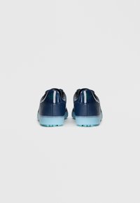 Marine sportieve schoenen met een gestructureerde leren bovenkant, voorzien van een doorschijnende blauwe rubberen zool en groene logo-accenten op de hiel.