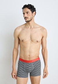 Fekete boxer alsónadrág geometrikus mintával, piros elasztikus derékpánt, rajta "PUMA" logóval, testhez simuló fazon, puha anyag.