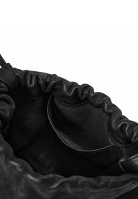 Sort læderpose med snor åben, der viser blødt indre og lille inderlomme, med detaljer ved den opsamlede øverste kant.