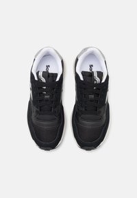 Zapatillas negras que combinan materiales de malla y cuero, con punta redonda, forro, diseño de cordones y una suela de goma texturizada con un acento blanco.