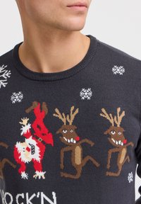 Dunkelgrauer, gestrickter Pullover mit festlichen Rentier- und Weihnachtsmann-Motiven in roten Akzenten, weißen Schneeflocken und dem Schriftzug "ROCK'N."