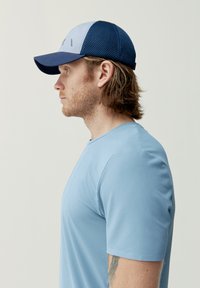 Modré sportovní tričko se strukturovanou tkaninou, doplněné dvoubarevnou čepicí s přední částí světle modré barvy a síťovanou tmavě modrou zadní částí.