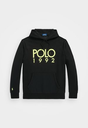 Černá mikina s kapucí s klokaní kapsou, stahovací kapucí a neonově žlutým nápisem "POLO 1992" na hrudi, plus malé logo na levém manžetě rukávu.