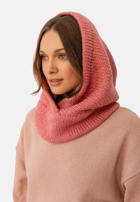 Dzianinowy różowy komin o wysokiej kołnierzu wykonany z miękkiej przędzy, charakteryzujący się grubą teksturą i gładkim wykończeniem, z delikatnym gradientem od jasnego do ciemniejszego różu.