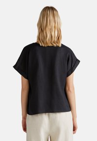 Haut à manches courtes en lin noir avec une coupe décontractée et un col rond, doté d'une texture lisse et d'un ourlet droit.