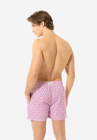 Costumi da bagno rosa con motivi geometrici blu; tessuto leggero; vita elastica; tasche laterali; lunghezza a metà coscia; etichetta visibile sul retro.