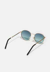 Gafas de sol redondas con un marco metálico dorado, lentes azul degradado y varillas de plástico negro. Almohadillas nasales ajustables para mayor comodidad.