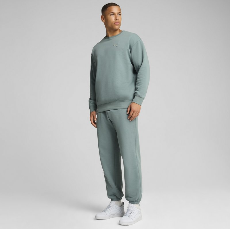 Lys grøn sweatshirt og matchende joggers lavet af blødt stof. Har et diskret logo på brystet og elastiske manchetter. Båret med hvide sneakers.