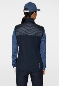 Laivastonsininen ja sininen eristetty takki, jossa on chevron-näyttö suunnittelu yläselässä, joustavat hihat ja istuva siluetti.