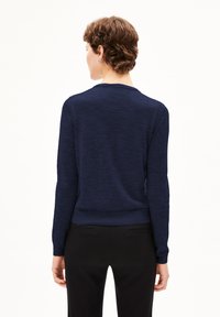 Marineblaues langärmliges Sweatshirt mit Rundhalsausschnitt, aus weichem, strukturiertem Strick gefertigt. Tailliert, glatte Oberfläche, minimale Details.