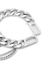 Bracelet en chaîne argentée avec des maillons entrelacés, un fermoir ovale et un accent de chaîne plus petite. Surface métallique lisse et réfléchissante.