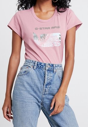 Lyserød bomulds t-shirt med et grafisk design med palmeblade og "G-STAR RAW" tekst. Kombineret med højtaljede blå denimjeans.