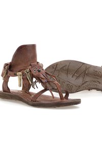 Brune lædersandaler med frynse detaljer, dekorative metal accenter og en tekstureret gummisål. Åbent design, ankelhøjde med remme.