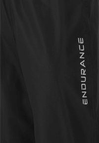 Svarta träningbyxor i lättviktsmaterial, med en slät yta och reflekterande "ENDURANCE"-logotyp på sidan.
