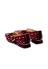 Zapatos de terciopelo burdeos de tacón bajo con tachuelas doradas, tacones cuadrados y correas con hebilla, mostrados desde la parte trasera sobre un fondo blanco.
