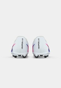 Ζεύγος άσπρων παπουτσιών ποδοσφαίρου με μαύρους σταυρούς, ροζ και μπλε λεπτομέρειες, και την ένδειξη "TIEMPO" στις φτέρνες, εμφανίζεται από το πίσω μέρος.