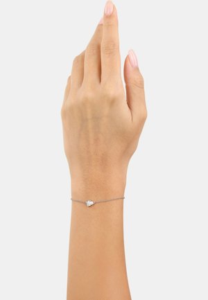 Braccialetto in argento con una piccola pietra preziosa trasparente, indossato al polso. Tono della pelle visibile, mano sollevata in una posizione rilassata.