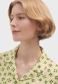 Korte mouwen shirt met een pastelroze basis, een groen bloemmotief, een geknoopte kraag en een zachte stofstructuur.
