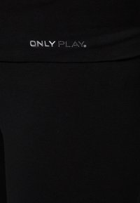 Zwarte legging gemaakt van rekbaar materiaal, met een logo "ONLY PLAY" in zilveren tekst op de tailleband. Eenvoudig en aansluitend ontwerp.