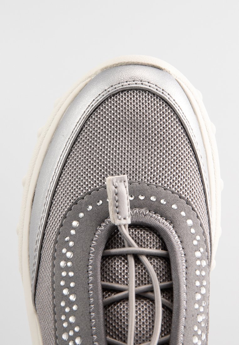 Grauer Sneaker mit einem strukturierten Mesh-Obermaterial, silbernen Akzenten, dekorativen Nieten und einer runden Zehenpartie auf einer dicken, cremefarbenen Sohle.