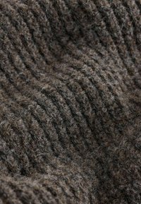 Wollstoff in Brauntönen mit gerippter Textur. Weiche, dicke Garne erzeugen ein gemütliches Erscheinungsbild mit subtilen Farbvariationen.