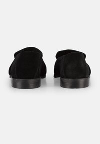 Black suede shoes with a flat wooden heel and open back design. Soft texture with visible stitching details and rounded edges.