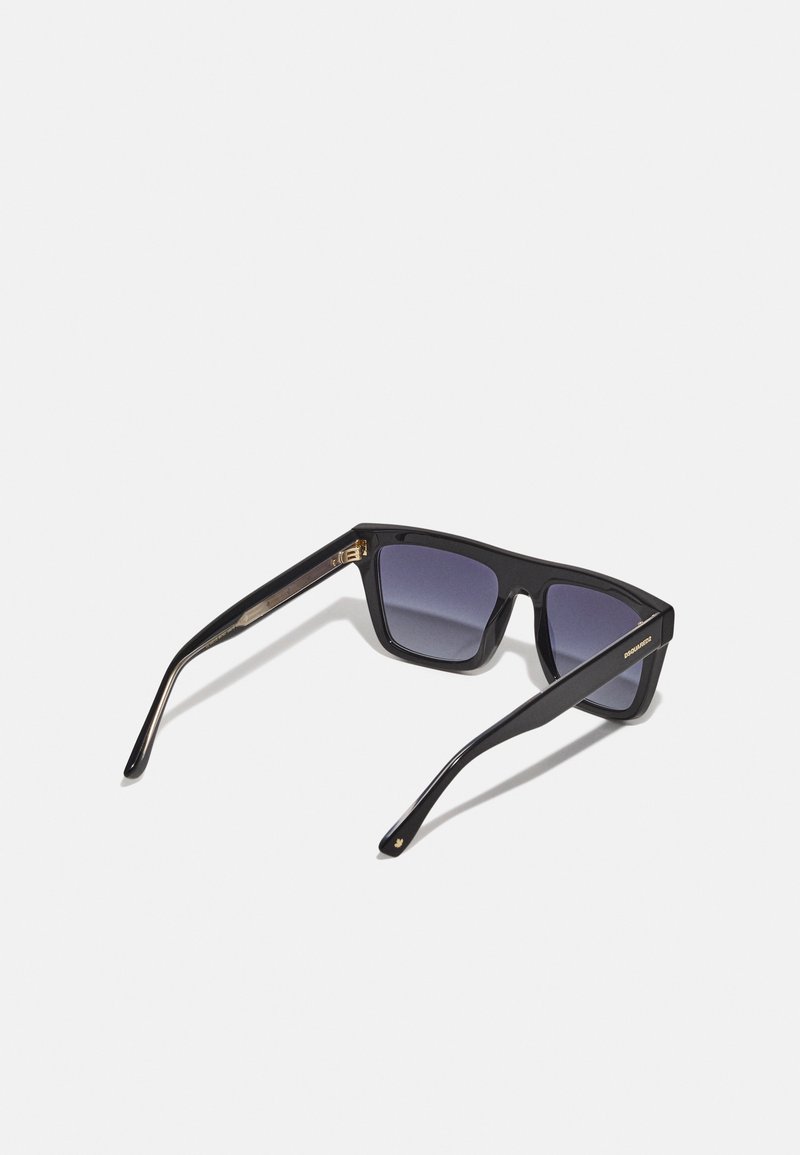 Lunettes de soleil noires avec des verres carrés, dotées d'une monture brillante et de verres gris dégradés. Comprend des accents dorés sur les branches.