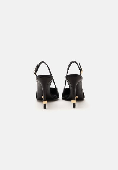 Ζευγάρι μαύρα ψηλοτάκουνα παπούτσια slingback με χρυσά αγκράφες, εμφανιζόμενα από πίσω σε λευκό φόντο.