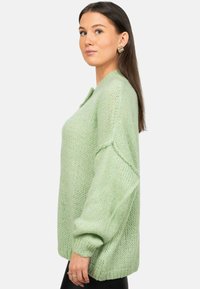 Maglione lavorato a maglia verde chiaro con una vestibilità ampia, dotato di maniche lunghe, scollo rotondo e un filato morbido e texturizzato.