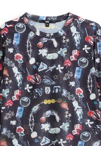 Chemise à manches longues multicolore avec un fond noir, ornée de divers motifs fantaisistes incluant des fleurs, des dés et des étoiles.