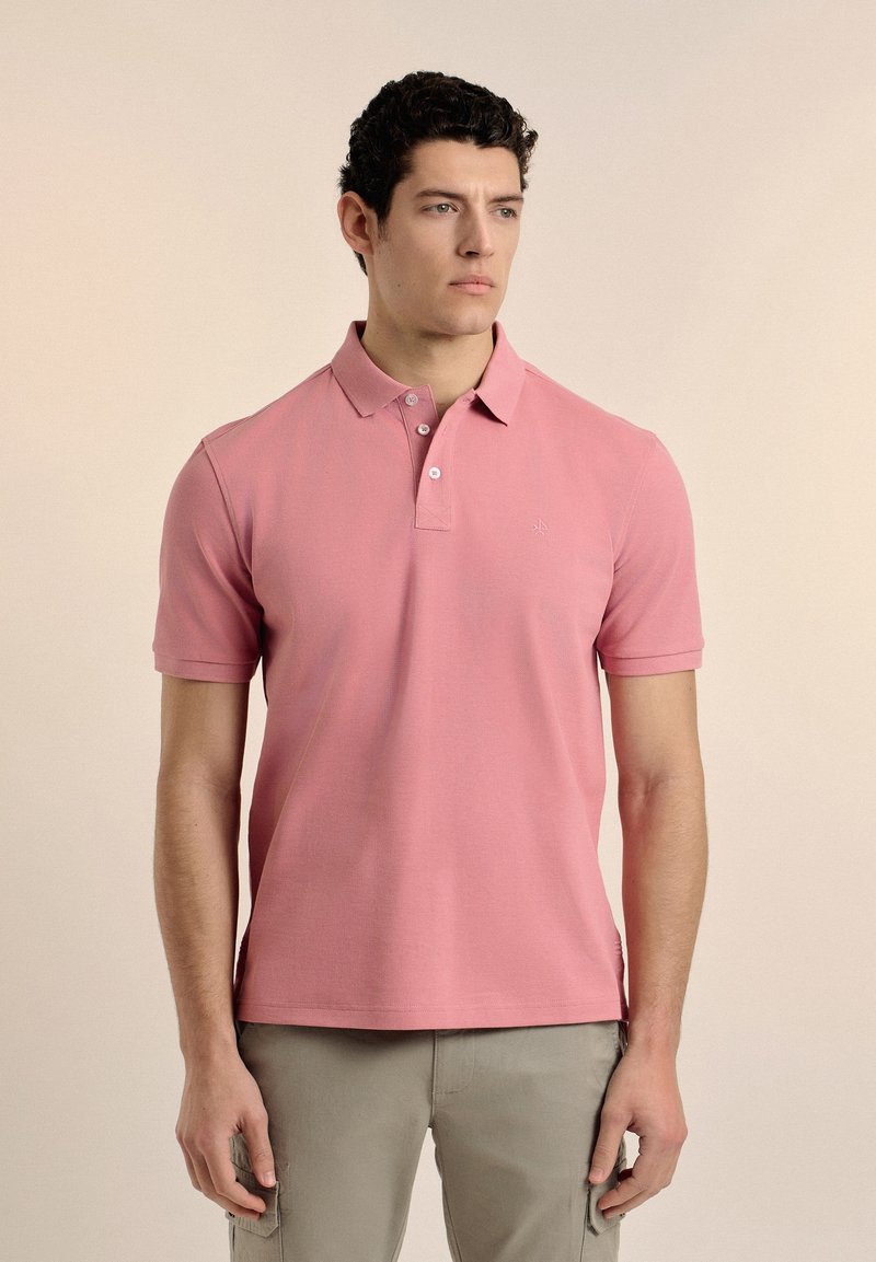 Camisa polo de manga corta en color rosa, confeccionada en tejido de algodón texturizado, con un cuello de dos botones y un pequeño logo en el pecho.