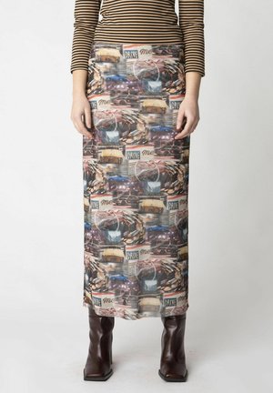 Maxirock mit einem Fotodruck von Oldtimern, aus leichtem durchsichtigen Material und mit taillierter Silhouette. Getragen mit braunen High-Heels.