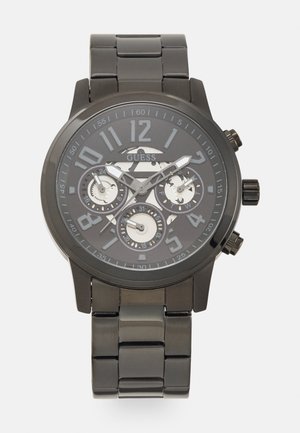 Montre-bracelet en métal noir avec un boîtier rond, de grands chiffres et trois sous-cadrans. Le bracelet présente un design de maillons polis.