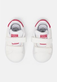 Vita lädersneakers med rosa detaljer, utrustade med två kardborremar, rund tå och en vadderad vit innersula. Varumärket logotyp på tungan.