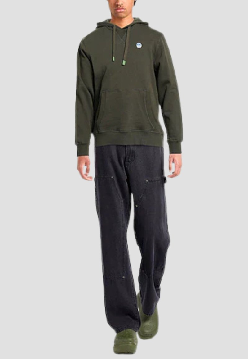Felpa verde scuro con tasca frontale e coulisse regolabili; abbinata a pantaloni neri larghi e zoccoli verdi. Design semplice e casual.