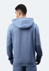 Felpa con cappuccio di colore azzurro chiaro, realizzata in un tessuto morbido con una finitura testurizzata, dotata di tasca a forma di marsupio e polsini e orlo a coste.