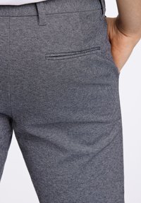 Grijze gestructureerde broek met een zijzak, een slanke pasvorm en een subtiel visgraatpatroon in de stof.