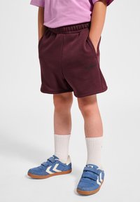 Burgundy shorts med dragsko i midjan och sidofickor, kombinerat med blå kardborreskor och vita ankelsockor.